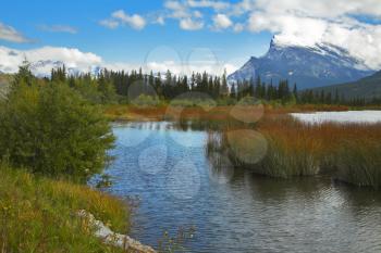 Charming shallow lake with small islands on a background of the Rocky mountains covered by a snow