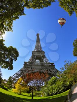 Hugel Eiffel Tower. At the foot of the tower is designed park with paths and pond. In the sky next to the tower floats giant balloon. The picture was taken Fisheye lens.  