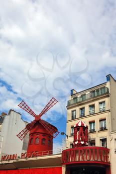 The most famous in the world of windmill - Parisian cabaret Moulin Rouge. Red Tower, mill wings and the words Moulin Rouge on the background of ordinary urban buildings
