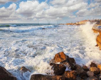 Magnificent storm in the Mediterranean. Storm waves crash against the rocks on the breakwater embankment. Tel Aviv, sunset, spring
