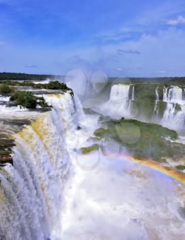  White whipped foam of water and a thin mist over the water.  Magnificent rainbow shines in the mist. The most high-water waterfall in the world - Iguazu. The picture is taken by lens Fisheye