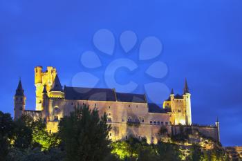 Palace of Spanish kings Alkazar in Segovia in twilight on a background of the cloudy sky