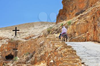 On the road, paved with stone, climbs on a donkey pilgrim in white clothes. Wadi Kelt, the road to the monastery of St. George