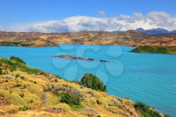 National Park Chile - Torres del Paine. Azure water of Lake Pehoe between green and yellow hilly coast