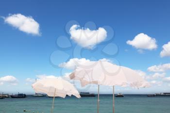 Tropical blue sea. The picturesque white parasols on the sea breeze