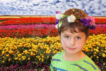 Field of multi-colored decorative buttercups Ranunculus Bloomingdale. Handsome boy in wreath of flowers posing on field background