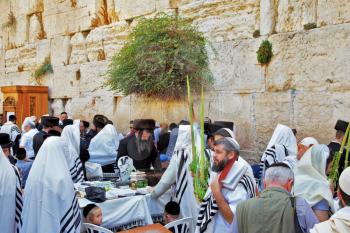 JERUSALEM, ISRAEL - SEPTEMBER 20, 2013: The Western Wall of the Temple in Jerusalem. Many religious Jews in traditional white robes tallit gathered for prayer. Morning Sukkot