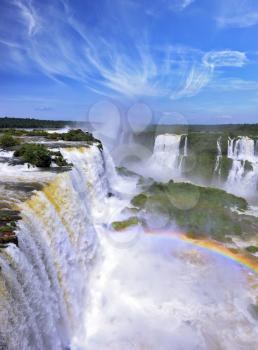  White whipped foam of water and a thin mist over the water.  Magnificent rainbow shines in the mist. The most high-water waterfall in the world - Iguazu. The picture is taken by lens Fisheye