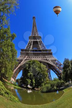 The majestic symbol of Paris - Eiffel Tower. In the sky next to the tower floats giant balloon. The picture was taken Fisheye lens