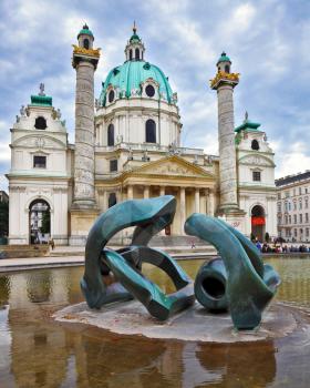 VIENNA, AUSTRIA - SEPTEMBER 26, 2013: On the square in front of church a big pond with a sculpture the Modernist style. Saint Karl Borromey's well-known church in Baroque style
