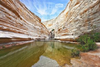 Striped sandstone walls and stream at the bottom of canyon. Unique canyon in the Negev Desert - Ein Avdat