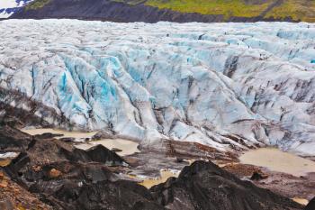 Skaftafell National Park.  Blue ice covered ground black volcanic ash. The southern part of the huge Vatnajokull glacier