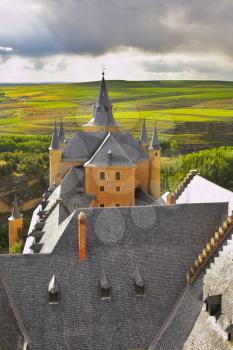 Roof and spikes medieval palace on a background green spring a field and roads