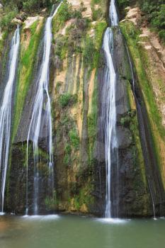 Unusual three-jet waterfall. Three parallel streams of water running down the steep slope and fall in oval pool