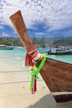 Boat Longtail decorated with silk tapes is moored in beach sand. Island Phi-Phi, Thailand

