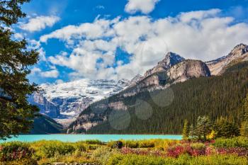 The picturesque promenade on the glacial Lake Louise. The emerald waters of the lake surrounded by mountains, glaciers and pine forests. Banff National Park, Canada