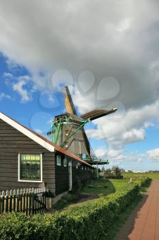 Pastoral landscape in Holland. A windmill and a barn on a green hillock