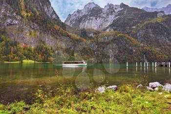 Cloudy day in the Bavarian lake Koenigssee. White tourist pleasure boat floats on the lake