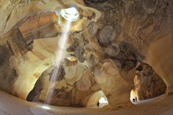 Clay huge caves are picturesquely shined with the sun from an opening above and lateral entrances. The ray of sunlight at an angle gets into space of a cave and forms  dazzling circle on a rough floor