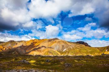 Multi-colored rhyolite mountains - orange, yellow, green and blue. Travel to Iceland in July, volcanic summer tundra