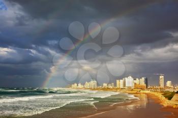  Storm cloud hanging over the sea, gorgeous huge rainbow crossed the sky. Promenade and beach in Tel Aviv