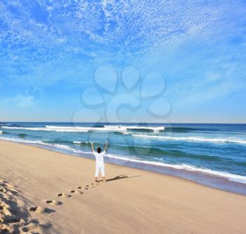  Middle-aged woman dressed in white doing yoga. Huge beautiful beach on the Atlantic coast. The seaside resort of Sintra