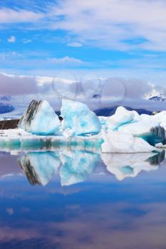 Early summer morning. Icebergs and ice floes are reflected in smooth water. Ocean ice lagoon Jökulsárlón