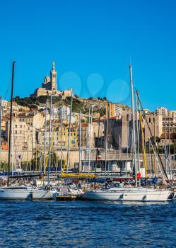 Marseilles. The water area of the Old Port - yachts, speedboats and fishing boats. On the hill - splendid Basilica of Notre-Dame de la Garde