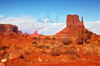 Famous rock - mitts of red sandstone. In the sky a rainbow. Magical landscape Monument Valley in Arizona