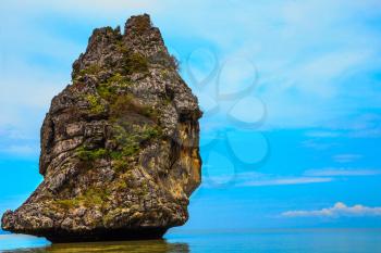 The haze of warm sea - background for huge stone cliff. The island is reflected in smooth surface of water. Island Sail in the ocean