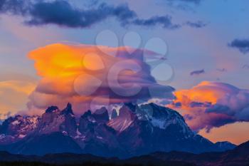 Incredible sunset in the national park Torres del Paine, Chile. The clouds are illuminated by the sun on the rocks Los Kuernos