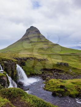 Iceland - the country of mountains, the rivers and falls. Cascade deep falls on the grassy mountains