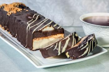 Delicious cheesecake with white and brown chocolate. The background is cup with tea. Professional bakery