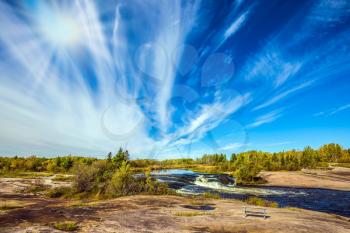 The concept of recreational and ecological tourism. Indian summer in Manitoba, Canada. Improbable plumose clouds and autumn sun over the river Winnipeg