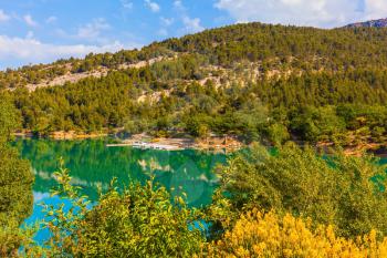 Mountain canyon Verdon in the French Alps. Smooth emerald river water reflects the sky and wooded shore
