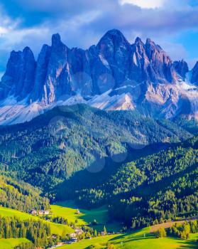  Alpine meadows. Magnificent serrated cliffs, green valley and small village in the Dolomites illuminate the summer sunset. The concept of eco-tourism in Tirol