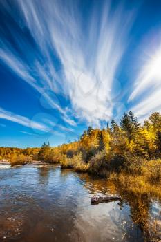 Incredible cirrus clouds over the Winnipeg River. Indian summer in Manitoba, Canada. Old Pinawa Dam Park. The concept of ecological and recreational tourism