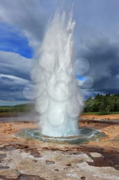 Gushing geyser Strokkur. High column of hot water and steam from the crater of the geyser. Iceland in the summer
