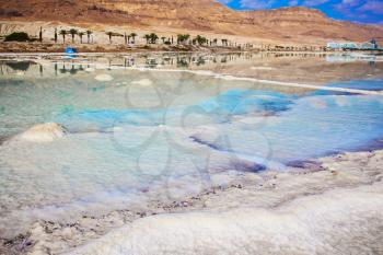 Hot summer day in Israel. The evaporated salt has developed into fantastic patterns. Walk on the Dead Sea. The concept of medical and ecological tourism 