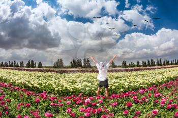  Stunned tourist in white shirt and bandana greets the rising sun. Flower kibbutz near Gaza Strip. Spring flowering buttercups