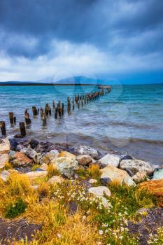 Strait of Magellan summer day. Waterfront, Punta Arenas. From the water stick piles of destroyed pier