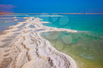 Summer day at the famous seaside resort on the Dead Sea. The evaporated salt has developed into fantastic patterns. The concept of medical and ecological tourism 