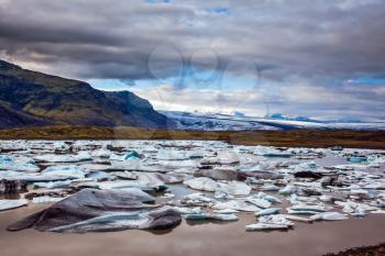 Summer in Iceland. The concept of extreme northern tourism. The picturesque lake with splinters of ice floes formed by thawed snow of grand glacier Vatnajokull 