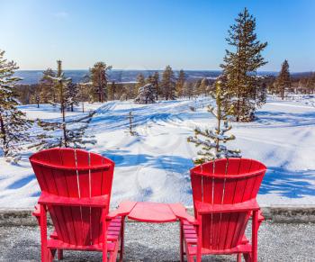 Soon Christmas. A pair of red comfortable armchairs for rest in the woods. Winter forest in the snow. The concept of active and extreme travel