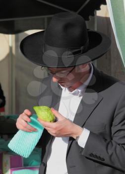 BNEI- BRAK, ISRAEL - SEPTEMBER 17, 2013: A young religious man - Jew closely examining citrus - fruit for the holiday of Sukkot. The traditional holiday bazaar before Sukkot