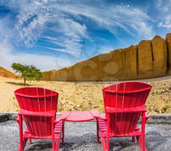 Two convenient red chaise lounges connected by small table stand for tourists. Walking route on  picturesque Black canyon