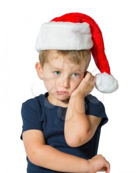  The child has sad blue eyes and fair soft hair. The charming little boy in red cap of Santa Claus. Photo executed on a white background
