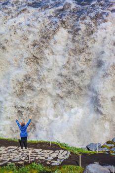Elderly woman admires the picturesque spectacle. Colossal roaring waterfall cascading into the abyss. Dettifoss, Iceland, Jokulsargljufur National Park 