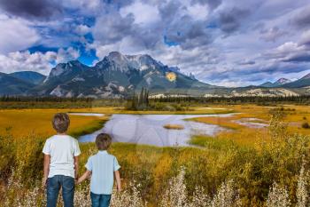 Magnificent landscape in the Rocky Mountains. Two boys admire the mountains and lakes. The concept of ecological and active tourism