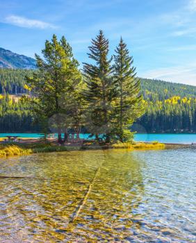 Golden Autumn in Canada. Lake Two Jack in the Rocky Mountains. Charming little island near the shore of the lake. The concept of ecological and active tourism
